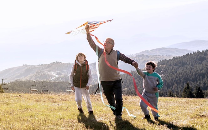 Grandfather Flying Kite With Grandkids