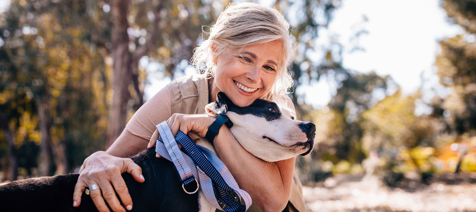 Affectionate Mature Woman Embracing Pet Dog In Nature