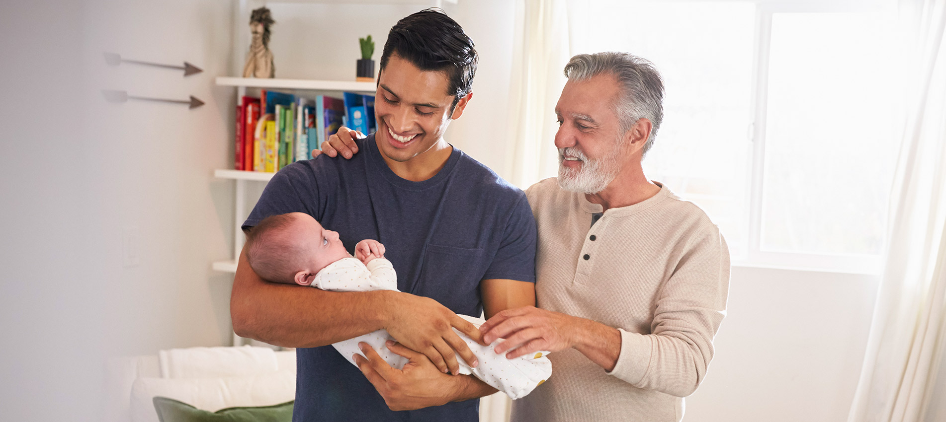 Proud Senior Hispanic Man Standing With His Adult Son Holding His Four Month Old Boy