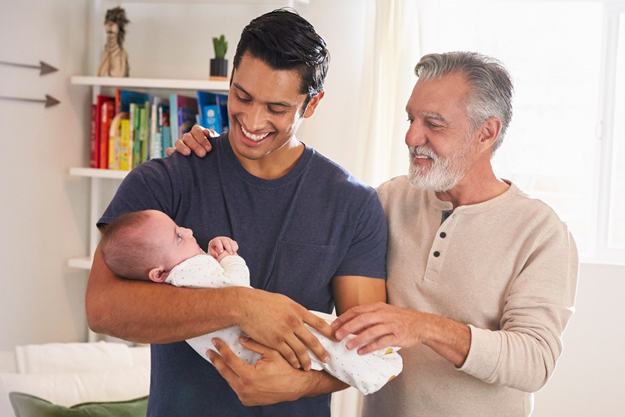 Proud Senior Hispanic Man Standing With His Adult Son Holding His Four Month Old Boy