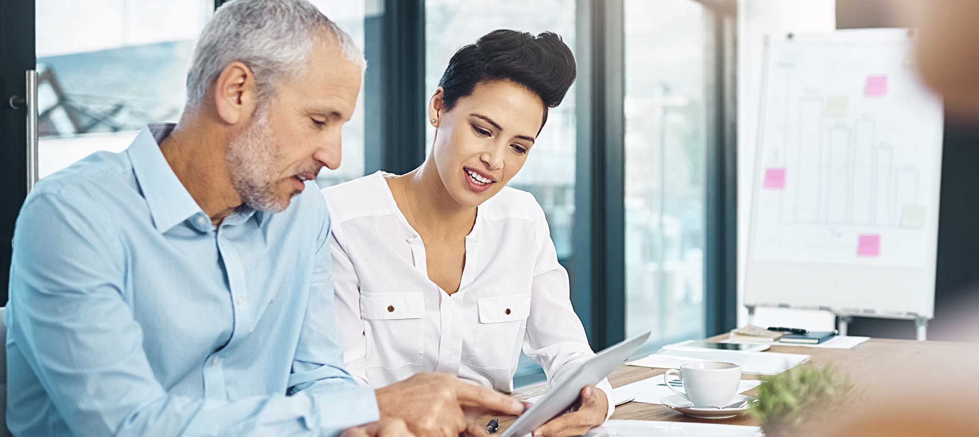 Group Of Coworkers Talking Together Over A Digital Tablet In A Meeting In An Office