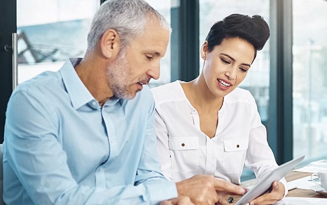 Group Of Coworkers Talking Together Over A Digital Tablet In A Meeting In An Office