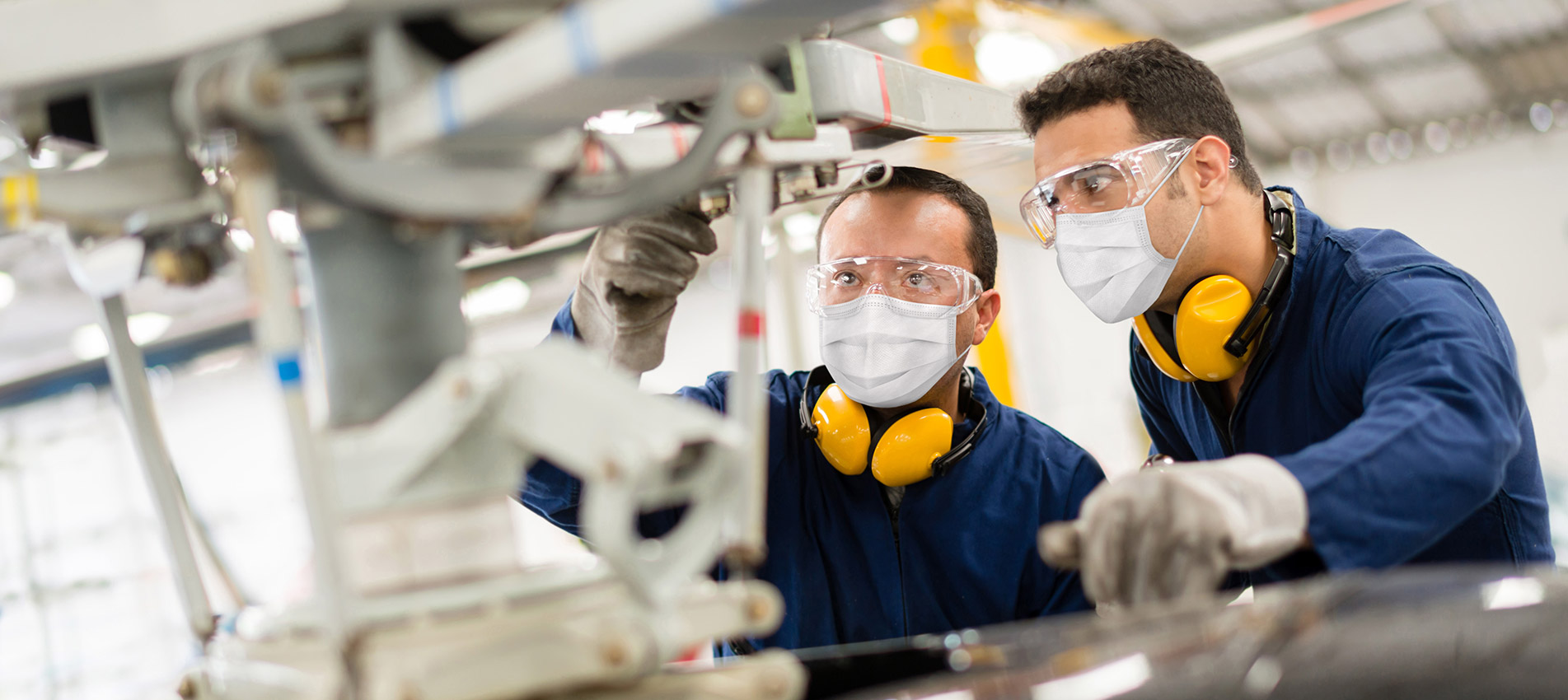 Mechanics Fixing A Helicopter While Wearing A Facemasks