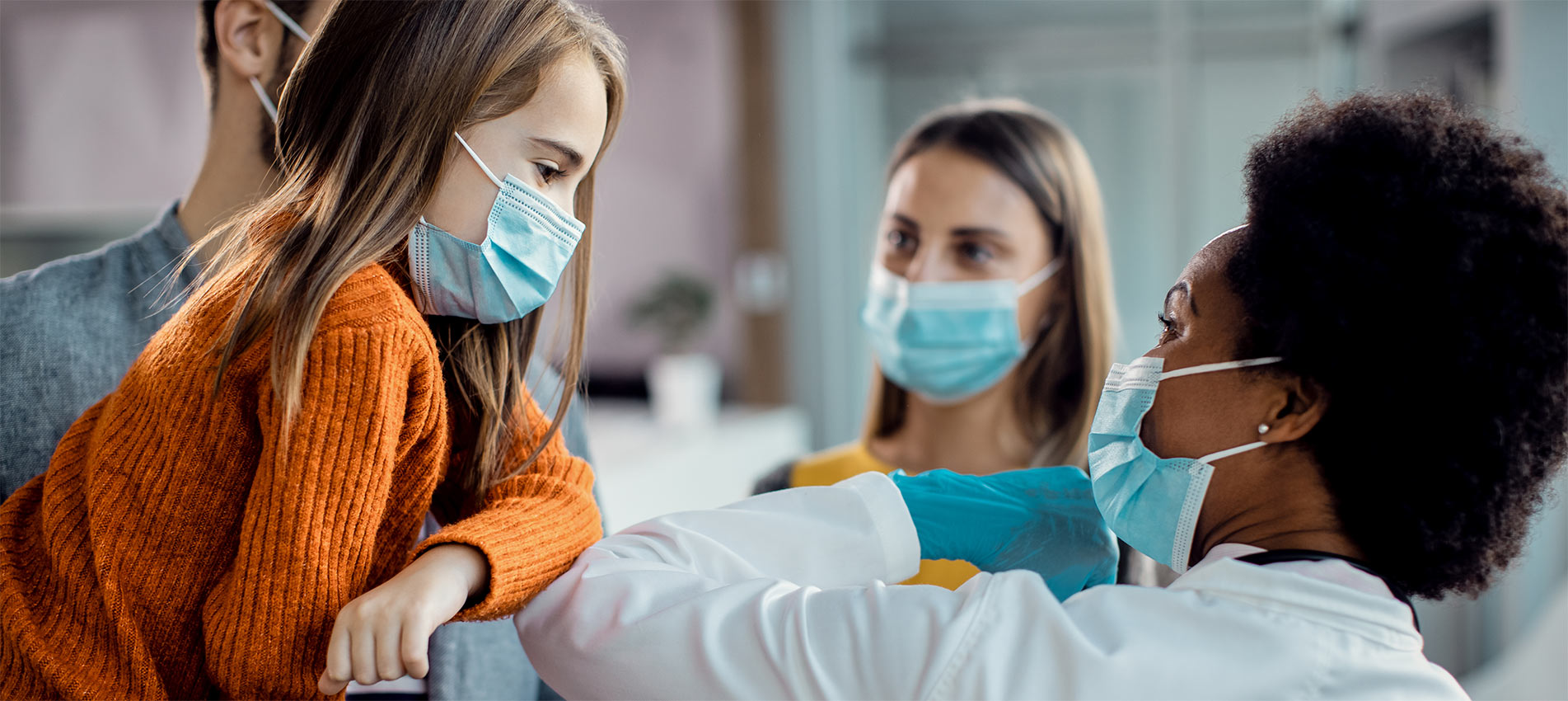 Little Girl And African American Female Doctor Elbow Bumping At Medical Clinic