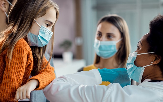 Little Girl And African American Female Doctor Elbow Bumping At Medical Clinic