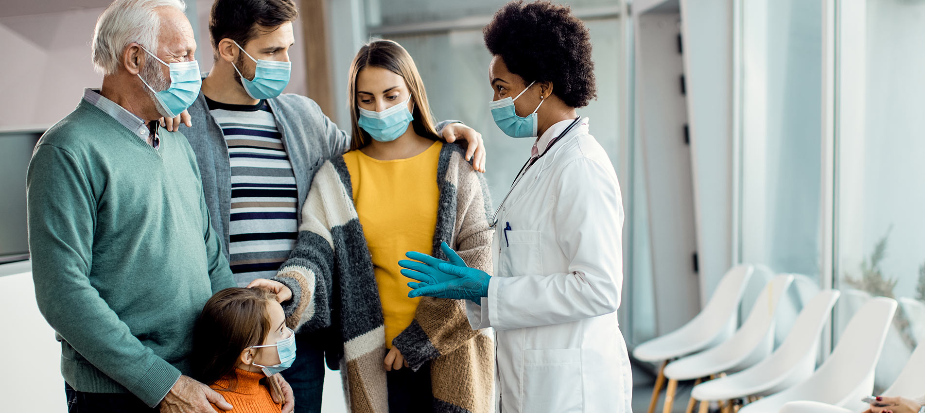 African American Doctor Talking To Extended Family At Medical Clinic During Coronavirus Pandemic