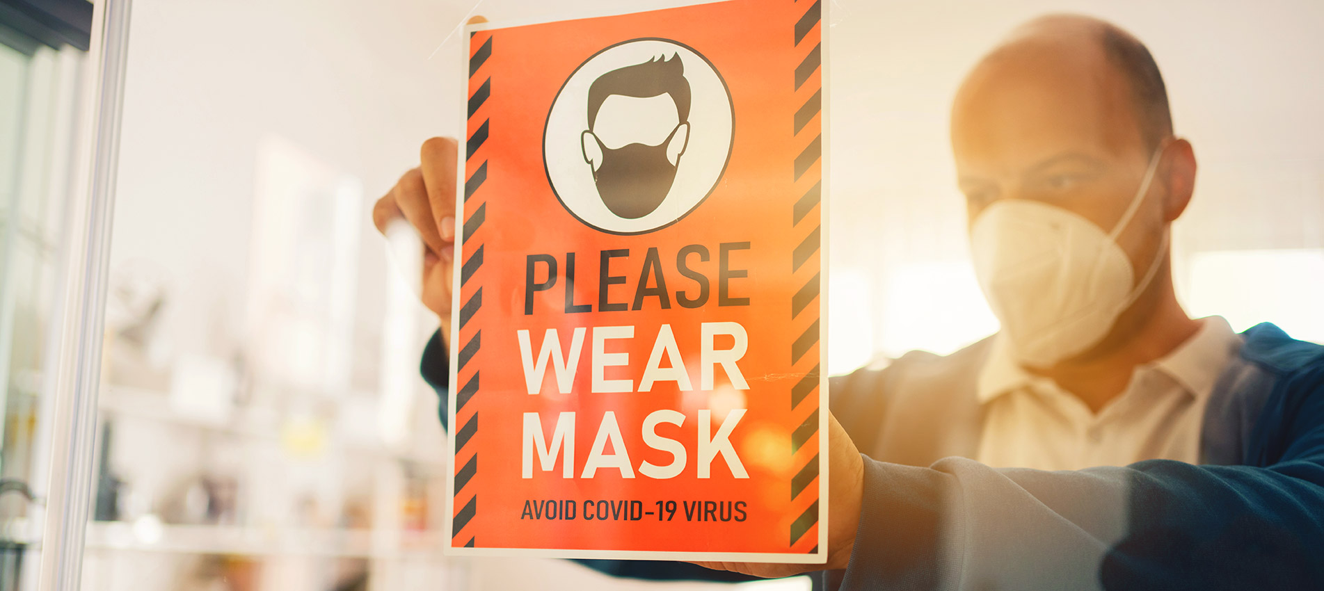 Man With Face Mask Putting Please Wear Mask Sign At Office