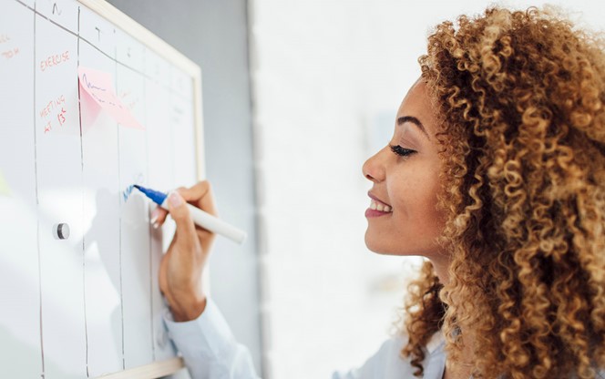 Latina Businesswoman Writing Schedule On A Whiteboard