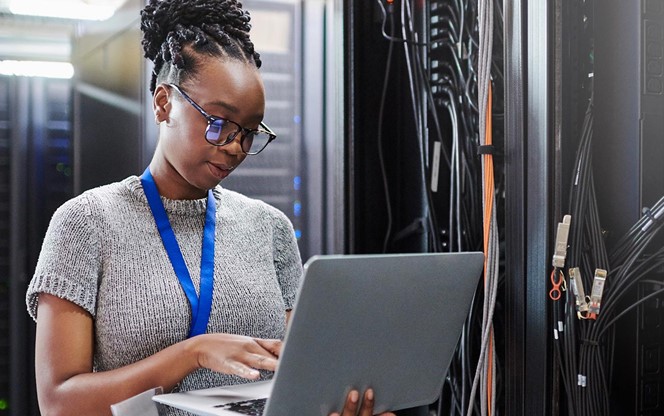 Young African Woman Using A Laptop In A Server Room
