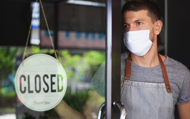 Chef In Safety Mask Hanging Up Sign Closed On Restaurant Door