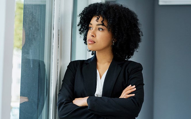 Young Businesswoman Looking Thoughtfully Out Of A Window In A Modern Office
