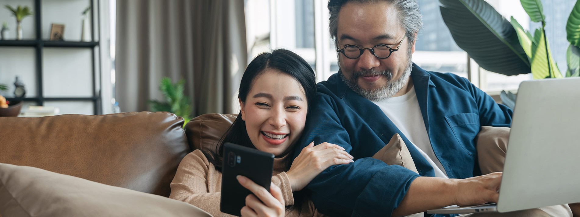 Asian Female Showing Smartphone To Husband In Living Room At Home