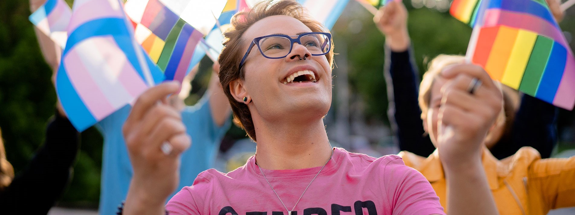Transgender Activist Holding Lgbtqi Flags In His Hands And Looking Up To The Sky