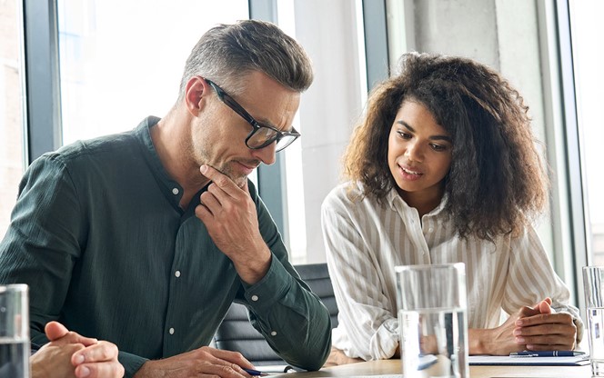 Focused Mature Businessman Reading Contract Considering Risks With Lawyers