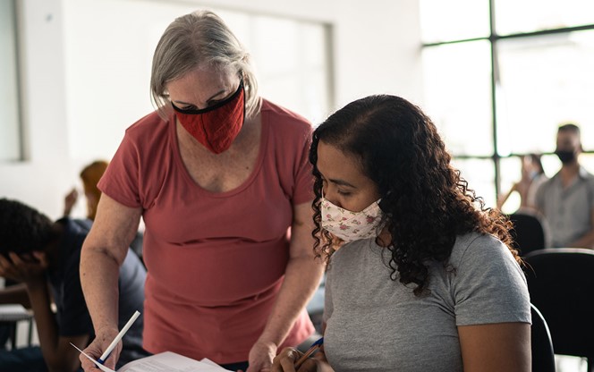 Teacher Helping Student At University Wearing Face Mask