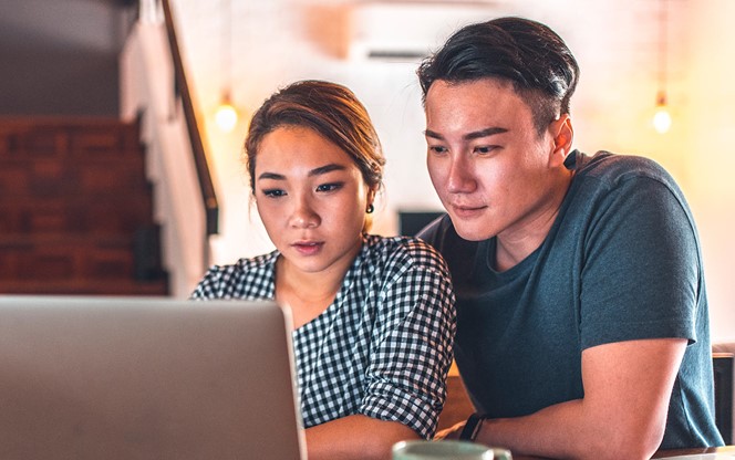 Asian Couple Using Laptop Working On Their Finances At Home