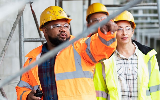 Woman Two Men Walk Under Scaffold At Construction Site