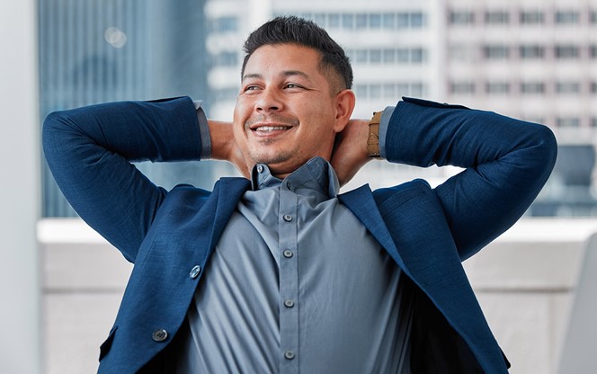 Young Businessman Sitting Alone In The Office With His Hands Behind His Head In Relief