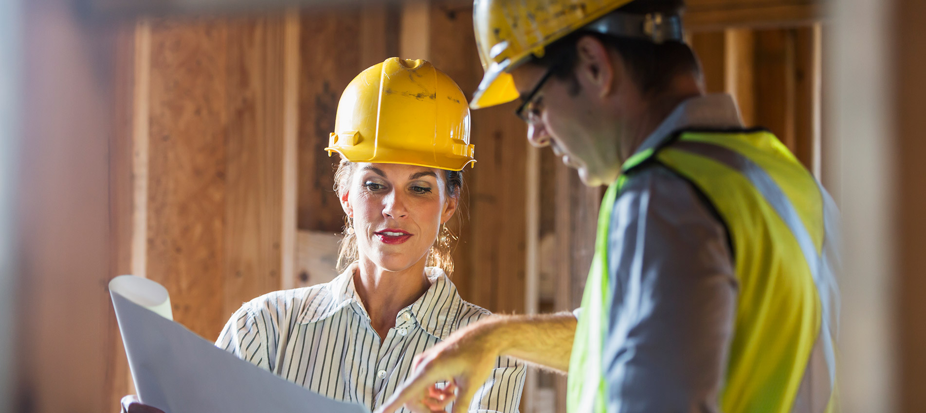 Workers Talking At Construction Site Reviewing Plans