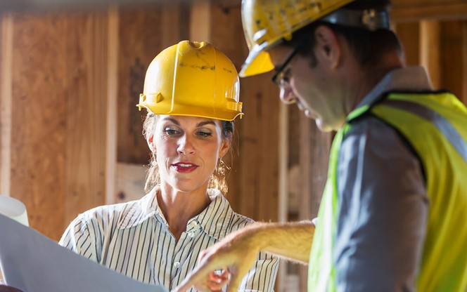 Workers Talking At Construction Site Reviewing Plans