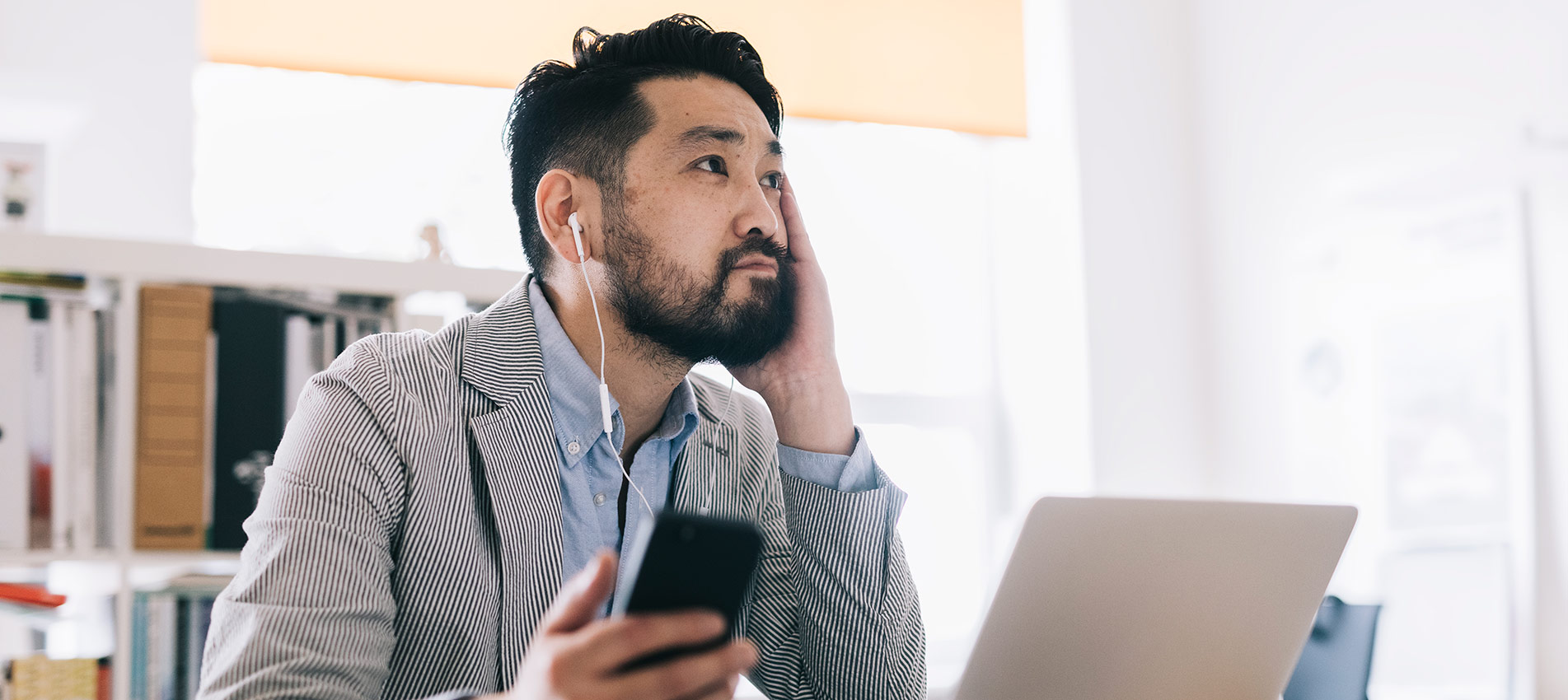 Asian Businessman Listening Educational Audiobook And Making Notes In The Laptop