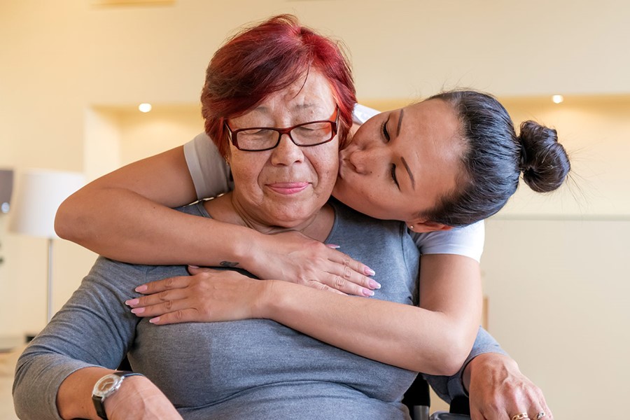 Senior Woman In A Wheelchair Is Receiving Treatment By Her Careful Daughter