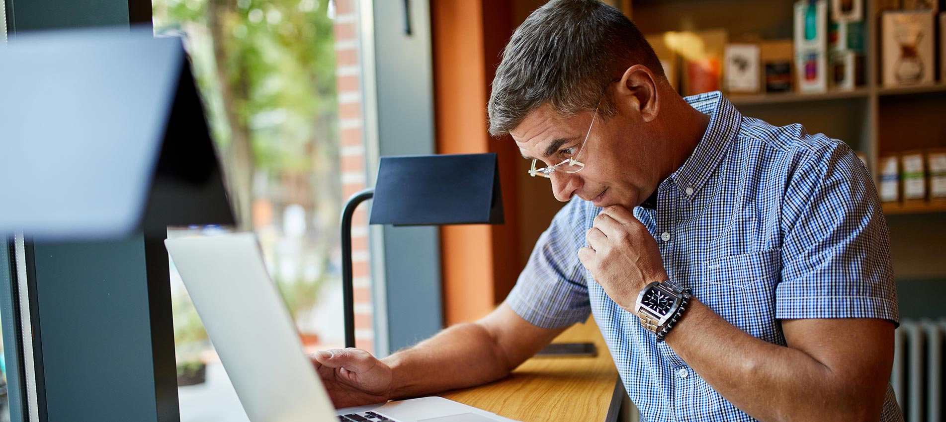 Mature Businessman Working On Laptop In Cafe