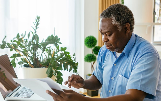 Senior African Man Sitting In His Home Office With His Laptop