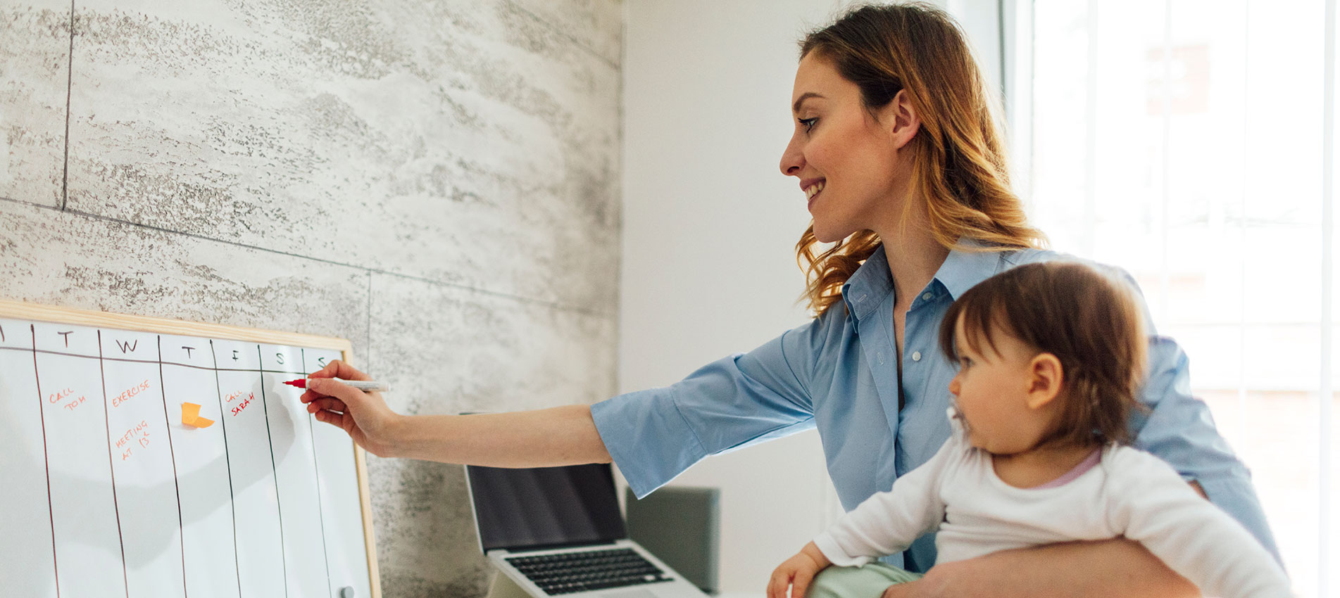 Mother Working From Home And Holding Her Baby