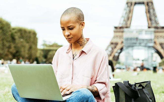 Mixed Race Woman Working On Laptop Outdoor By The Eiffel Tower