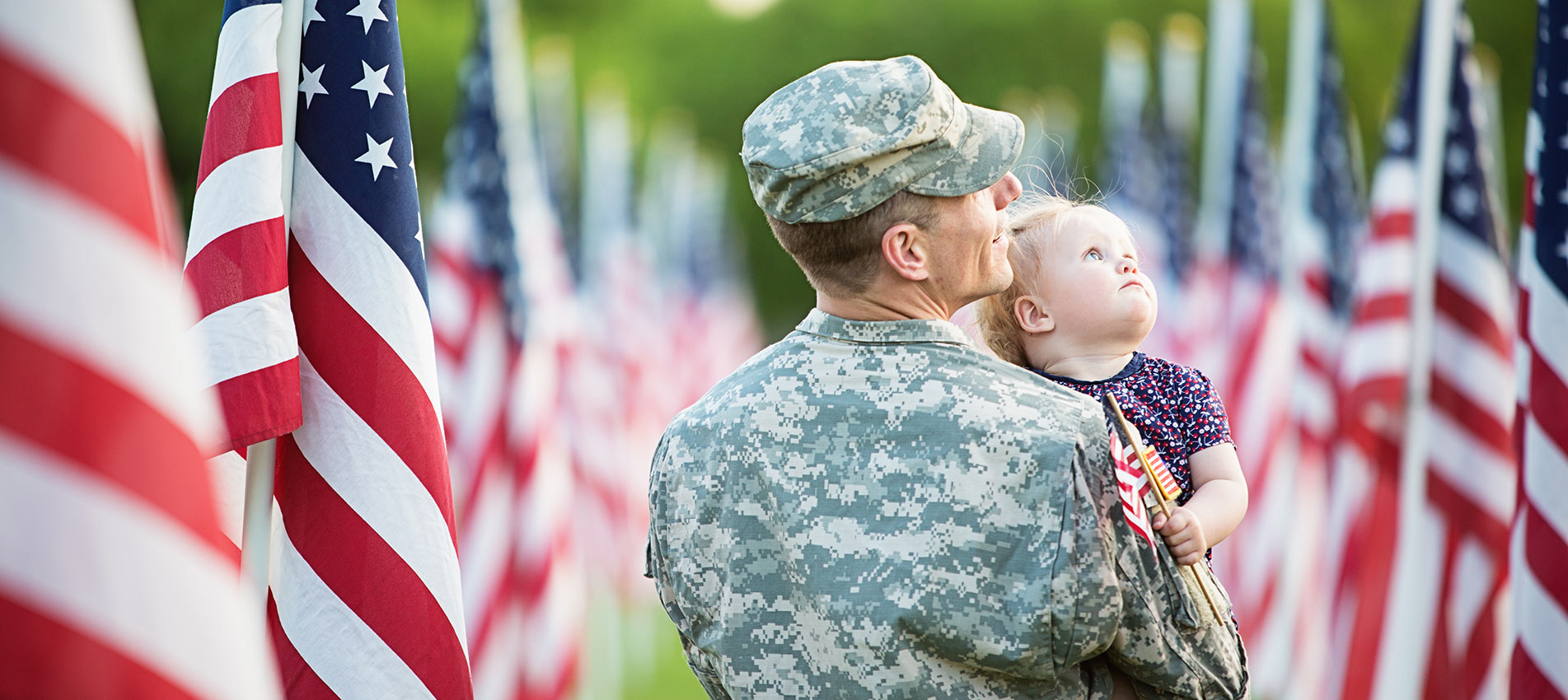 American Soldier Looking At Flags With His Daughter