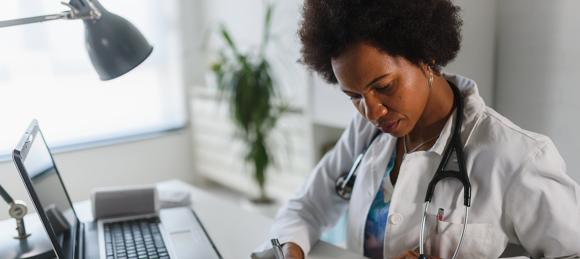 Woman Doctor With Stethoscope Looking At Medical Papers At Her Office