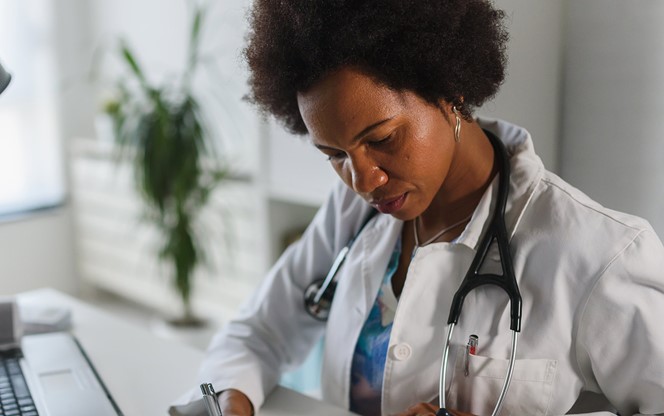 Woman Doctor With Stethoscope Looking At Medical Papers At Her Office