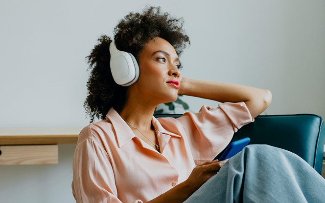 Relaxed Young Woman With Headphones On Sitting And Listening To Her Favorite Podcast
