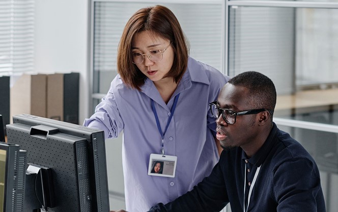 Asian Woman Discussing New Software With Colleague