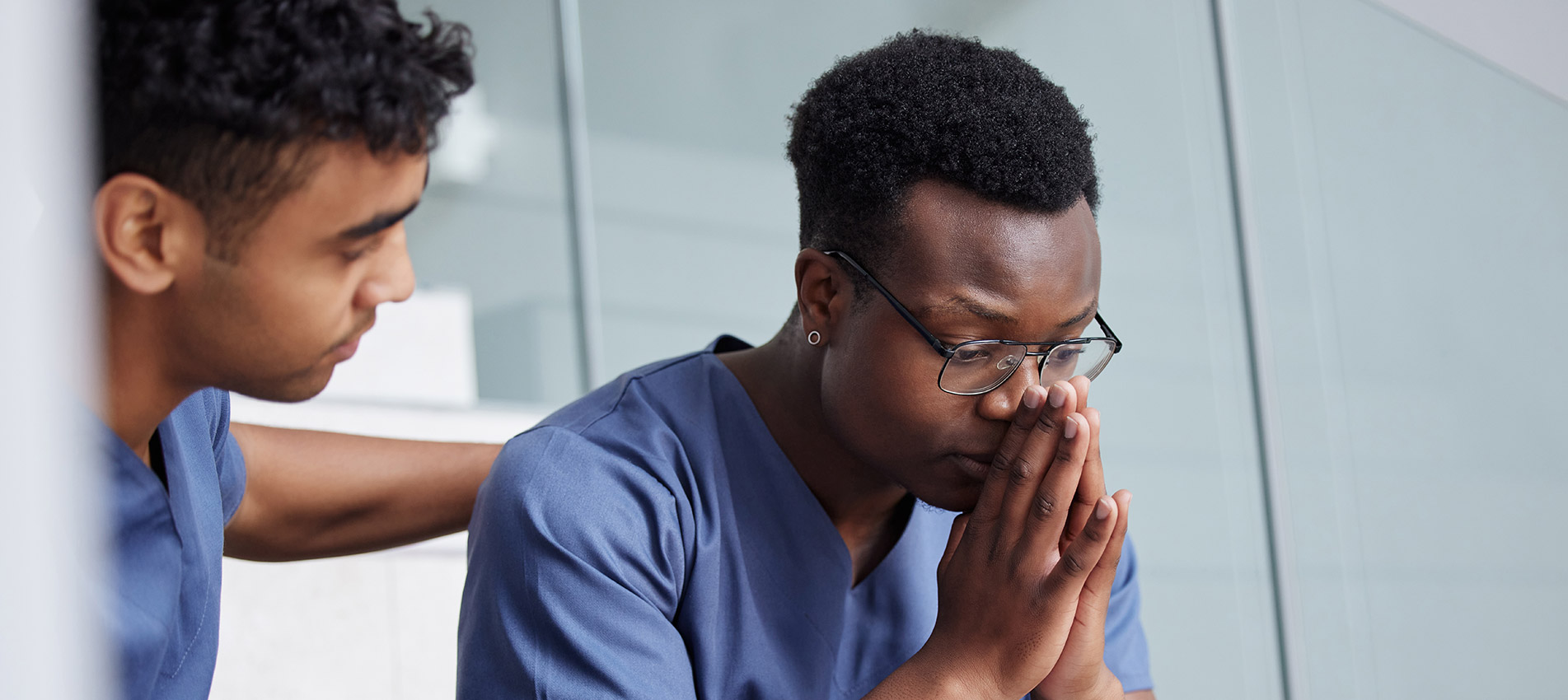 Young Male Doctor Consoling A Coworker At Work