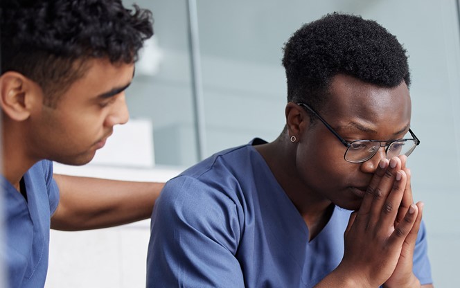 Young Male Doctor Consoling A Coworker At Work