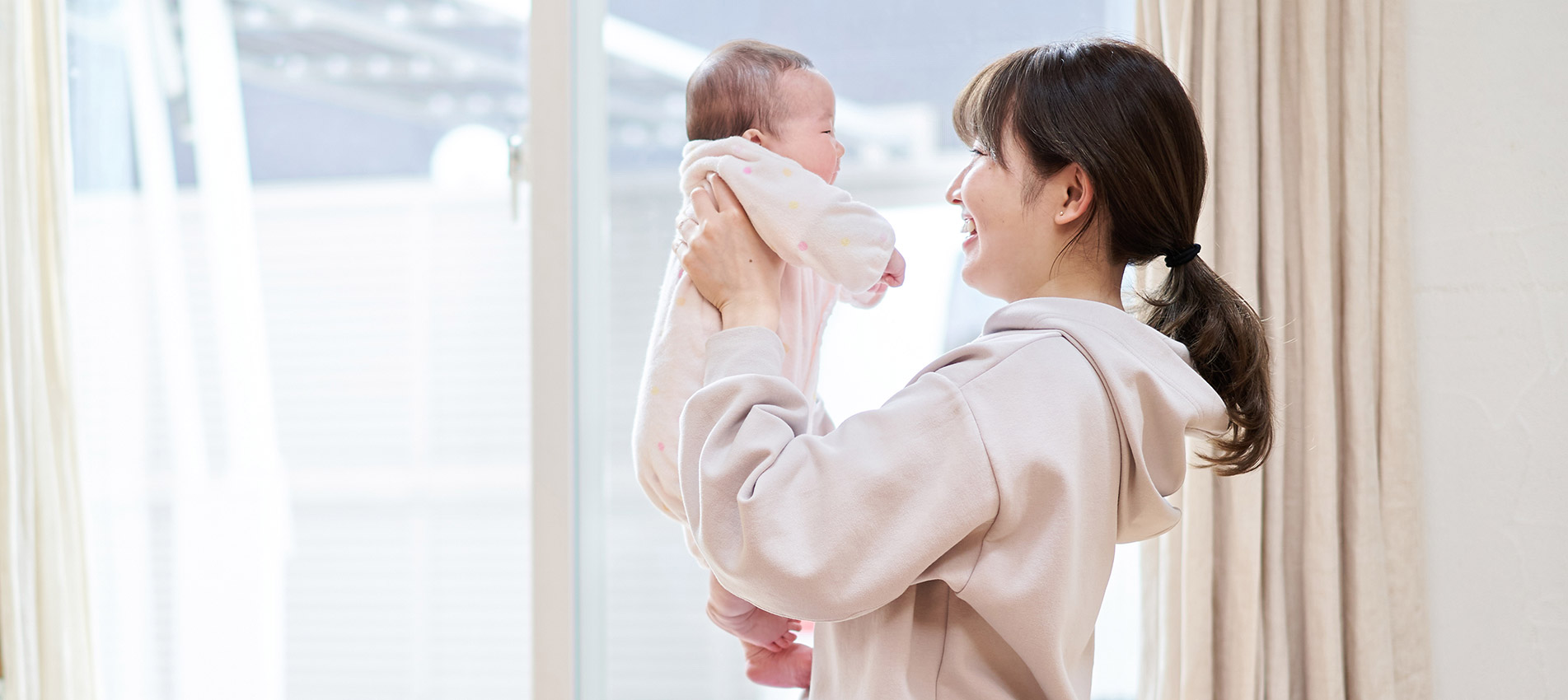 Asian Mom Holding A Baby In The Living Room