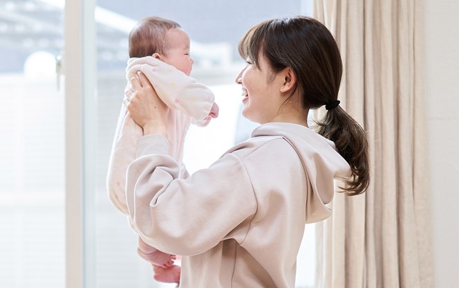 Asian Mom Holding A Baby In The Living Room