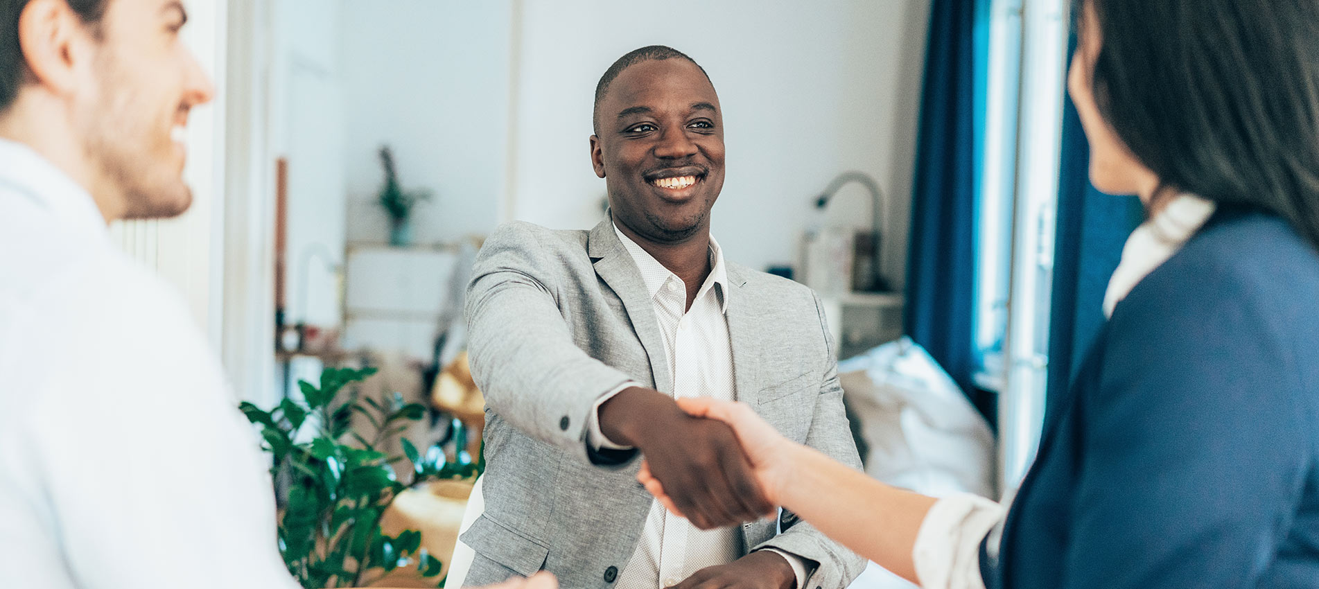 Business People In The Office Sitting On Desk And Shaking Hands