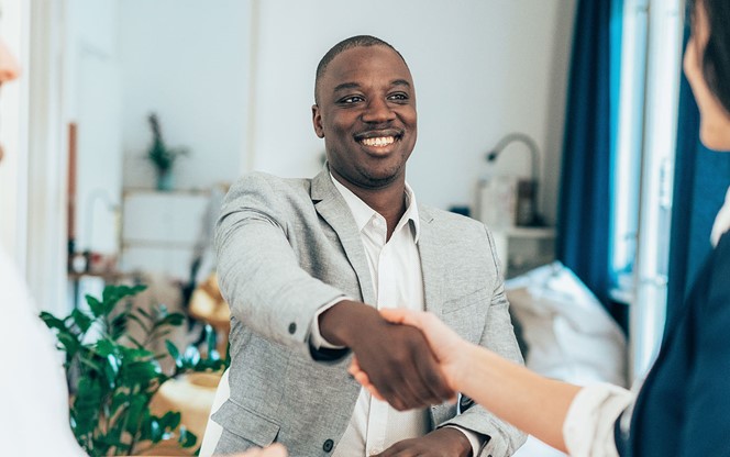 Business People In The Office Sitting On Desk And Shaking Hands