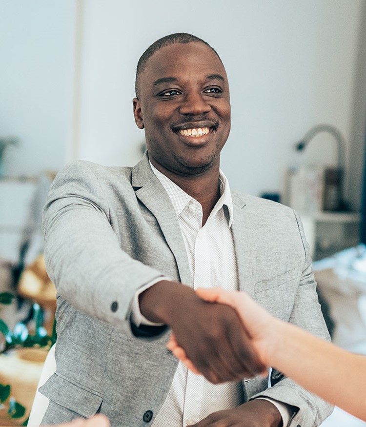Business People In The Office Sitting On Desk And Shaking Hands