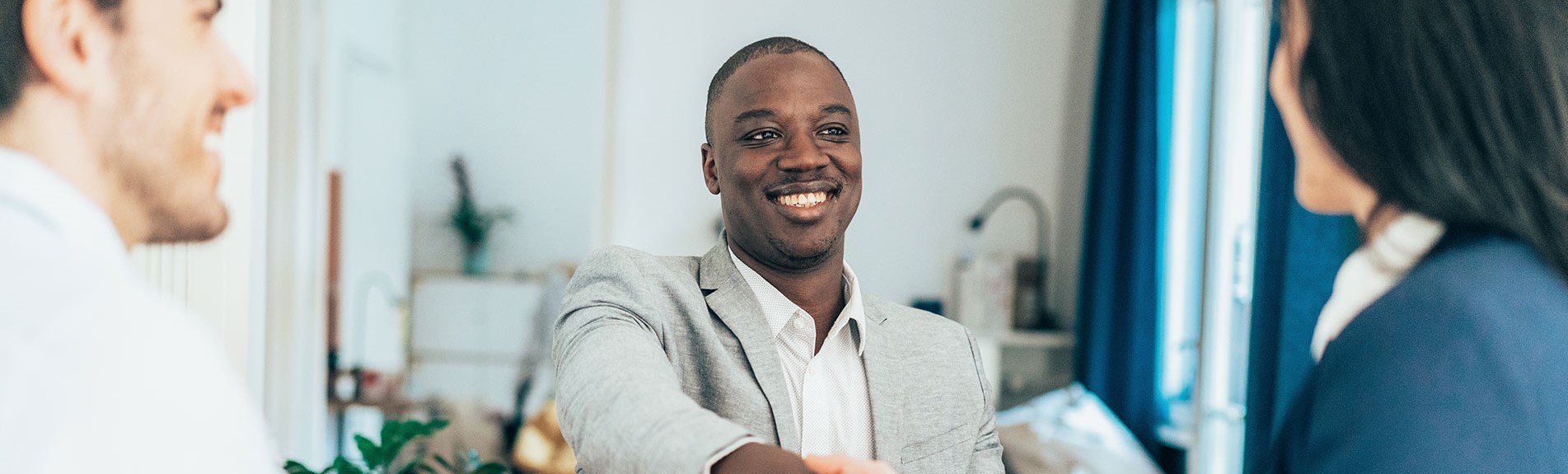 Business People In The Office Sitting On Desk And Shaking Hands