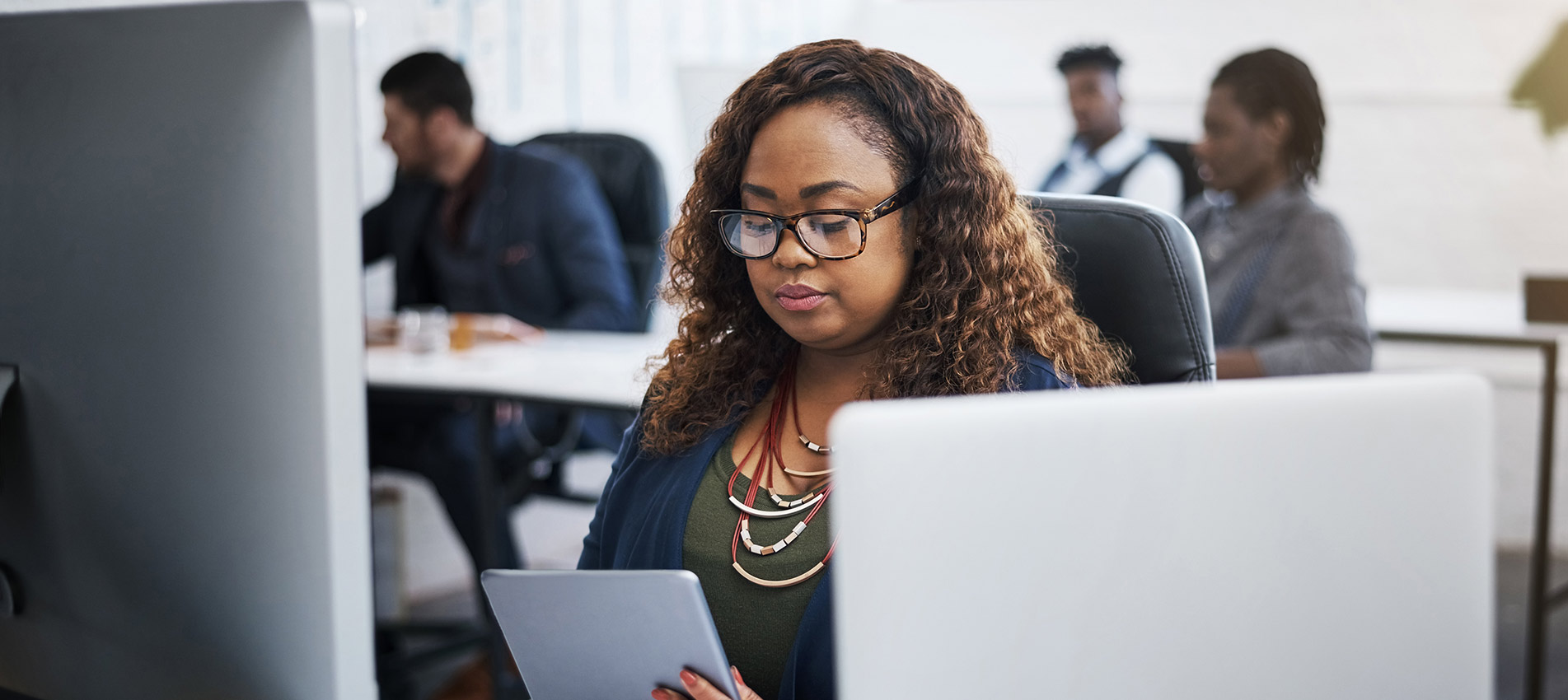 Young Businesswoman Using A Digital Tablet At Her Desk In A Modern Office