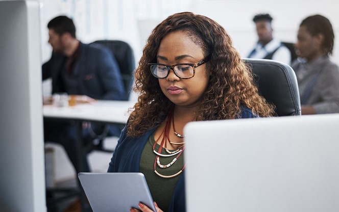 Young Businesswoman Using A Digital Tablet At Her Desk In A Modern Office