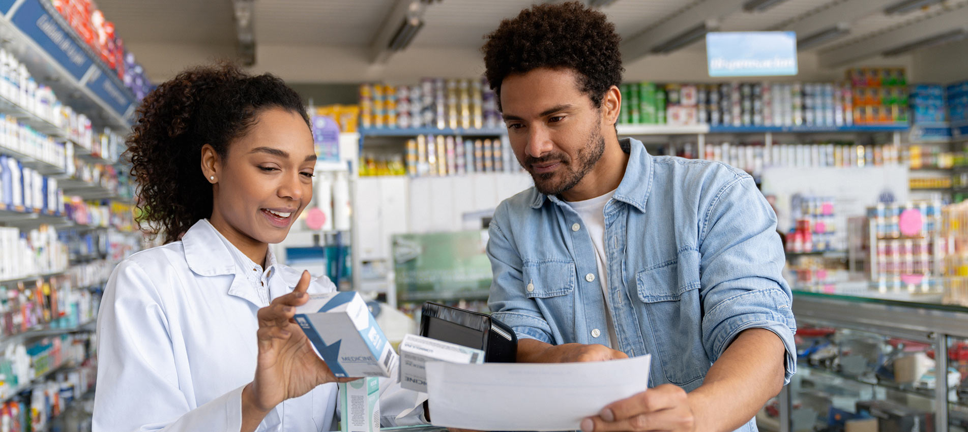 Female Pharmacist Checking Prescription Medicine With A Customer At A Pharmacy