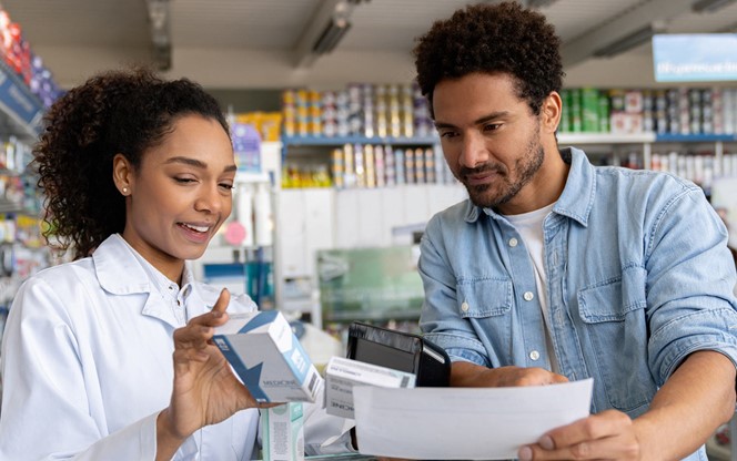 Female Pharmacist Checking Prescription Medicine With A Customer At A Pharmacy