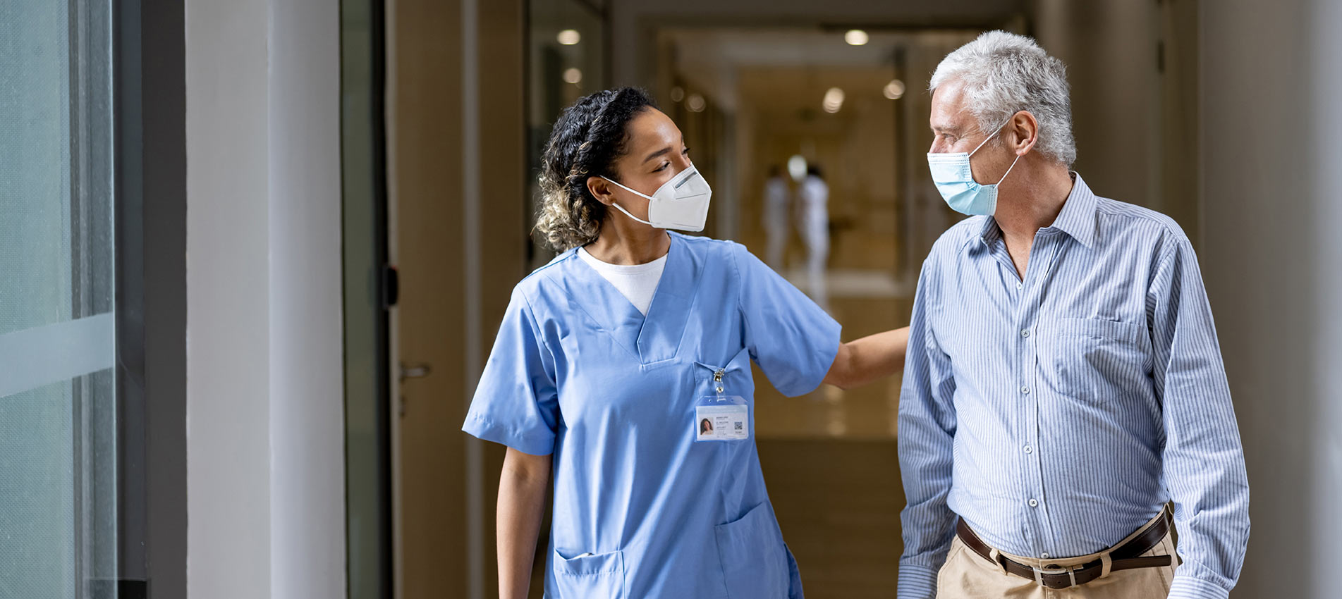 Doctor Talking To A Patient In The Corridor Of A Hospital While Wearing Face Masks