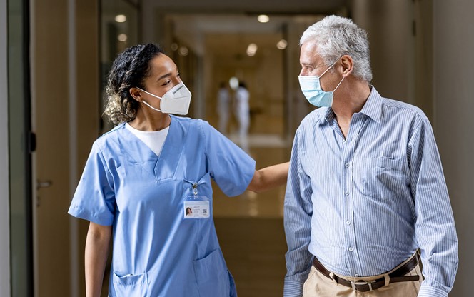Doctor Talking To A Patient In The Corridor Of A Hospital While Wearing Face Masks