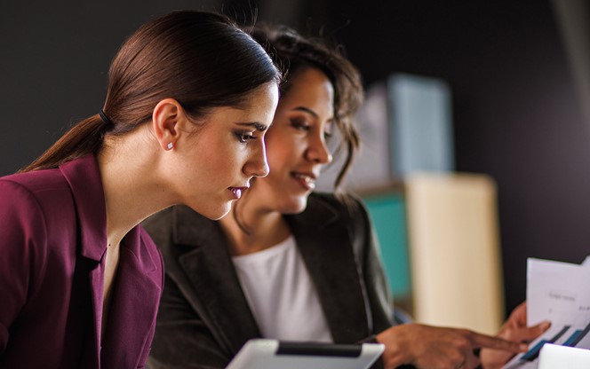 Two Businesswomen Having A Project Meeting Reviewing Data And Discussing Strategie
